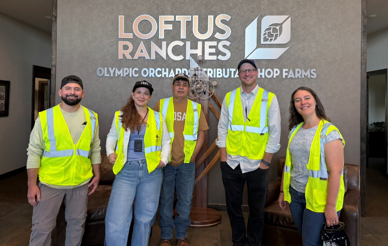Five people in yellow safety vests stand in front of a wall with letters reading Loftus Ranches.